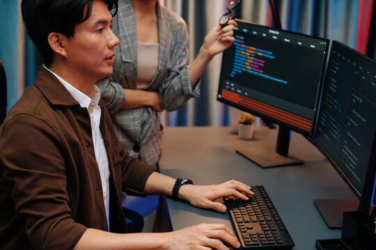 IT developers discussing with point to intelligent website development coder system running data online two screens information technology at neon light room at modern office. Infobahn.