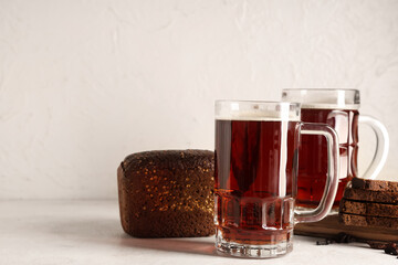 Glasses of fresh kvass and slices of bread on white background