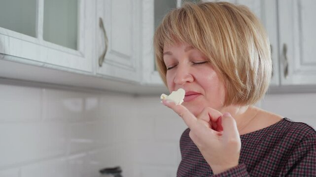 woman in plaid cloth holding white creamy butter in hand with satisfactory expression on face in kitchen feeling happy with quality ingredient, enjoying cooking experience in modern home setting