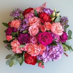 A vibrant floral arrangement featuring roses, peonies, hydrangeas, and carnations in shades of pink, purple, and red. 