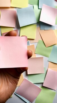 A vibrant array of sticky notes is scattered across a surface, while a hand gracefully holds one note in a dynamic, creative workspace