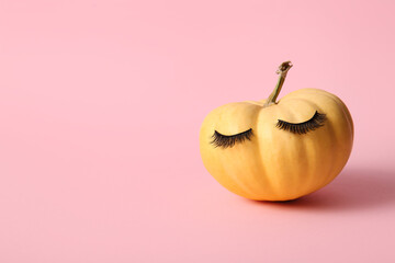 Pumpkin with false eyelashes on pink background