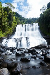 Fototapeta premium Majestic Waterfall Surrounded by Lush Greenery in Serene Landscape