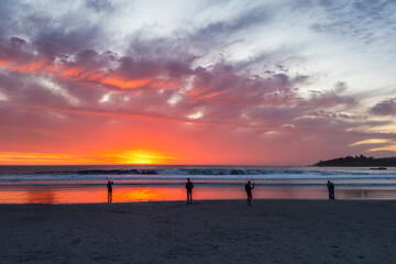 Fototapeta premium People watching sunset at Carmel-by-the-Sea Beach with vivid glowing sky and ocean waves