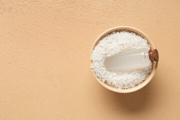 Bowl with bottle of rice water and grains on color background