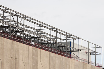 Fototapeta premium concrete building and metal beam frame during construction against grey sky