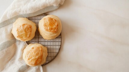 Three freshly baked pastries on a wire cooling rack. the pastries are golden brown in color and have a flaky texture.