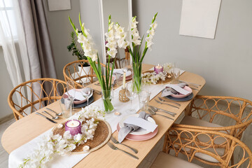 Beautiful table setting with white Gladiolus flowers and burning candles in room