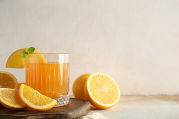Glass of fresh orange juice with mint and cut fruits on white background