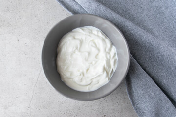 White bowl with natural yogurt on the wood table.