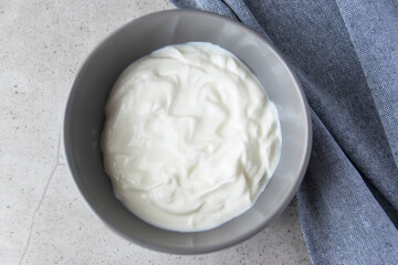 Gray bowl with natural yogurt on the stone marble table.