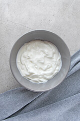 Gray bowl with natural yogurt on the stone marble table.