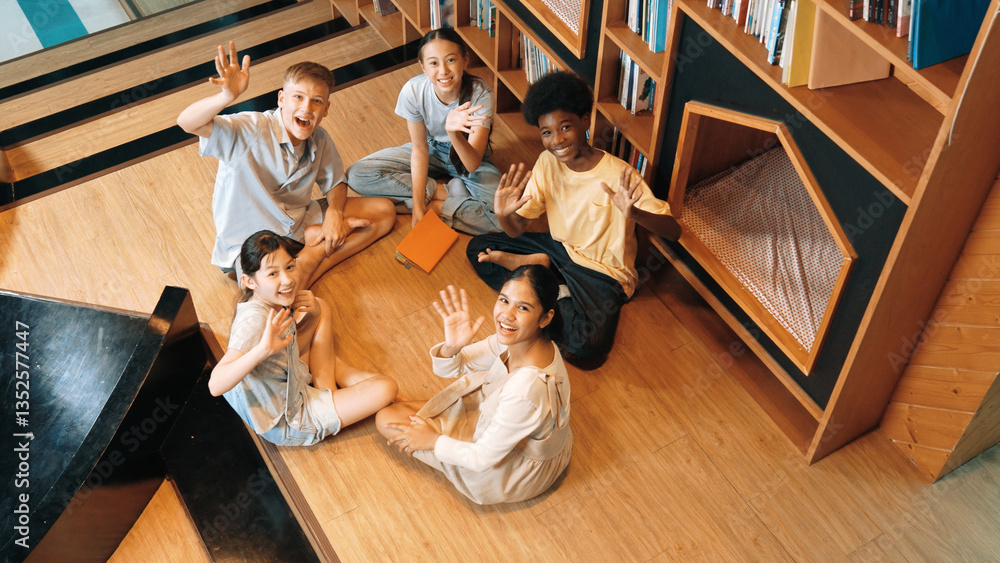 Poster top view of diverse children sitting in circle while looking at camera and waving hands at library s