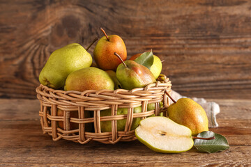 Wicker bowl with sweet ripe pears on wooden background