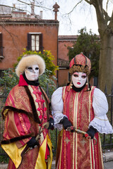 Venice, Italy - People dressed in carnival masks are photographed by tourists in the scenery of the ancient Venetian palaces