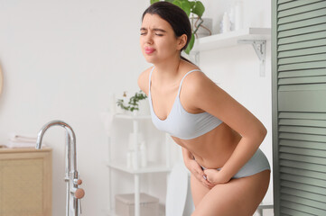 Young woman suffering from menstrual cramps in bathroom