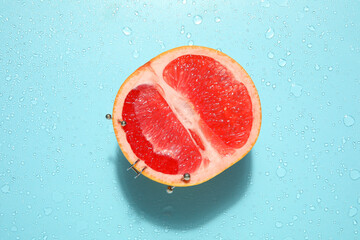Half of grapefruit with piercing on wet blue background