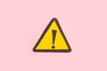 Yellow triangle with exclamation mark on pink background
