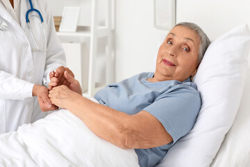 Obraz premium Senior woman with doctor holding hands in hospital room