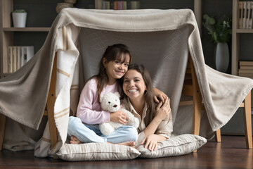 Living room adventure. Family portrait happy friendly young mom nanny cute little daughter looking...