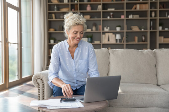 Easy finance management. Smiling senior woman use notebook to pay utility bills taxes make online financial transactions according to budget plans enjoy simple bookkeeping from home office. Copy space