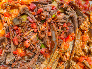 Top view of dish with meat, vegetables, and rich sauce. Meat stew, colorful tomatoes and peppers in savory sauce. Culinary tradition, hearty meals concept. Close up