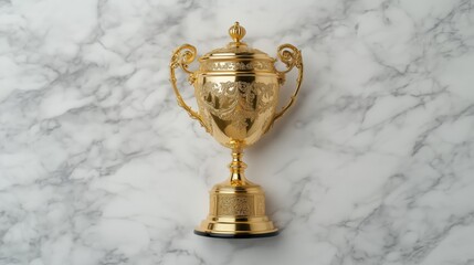 A shiny golden trophy with intricate designs placed on a marble surface.