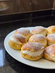 Homemade Berliner donuts pastries with powdered sugar and cream filling. Delicious Berliner or Krapfen buns dessert served on a white plate. Jam doughnut, German pastry and sweet concept