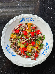 Colorful black bean salad with roasted peppers, herbs, and pomegranate on decorative plate. Fresh mediterranean black eyed pea salad. Healthy eating, nutrition and wholesome meals concept