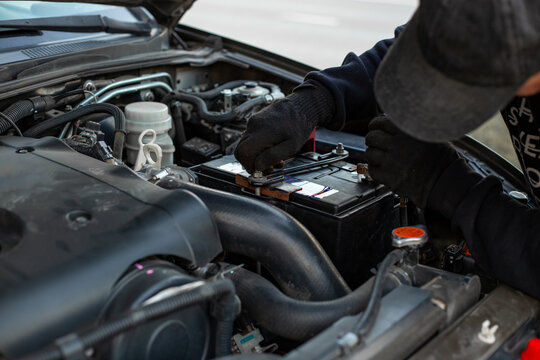 Replacing a car battery. A man installs a battery by installing a battery mounting bracket