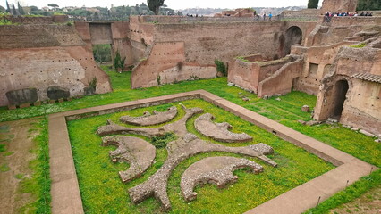Rome, Italy - 4.4.2018: Aerial view of ancient ruins in the Palatine Hill area, showcasing archaeological remains amidst lush greenery and flowers highlighting the historic landscape