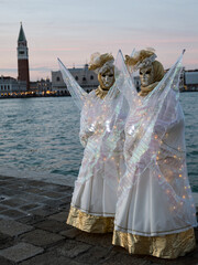 Obraz premium Venice, Italy - People dressed in carnival masks are photographed by tourists in the scenery of the ancient Venetian palaces