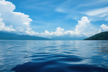 Obraz premium Calm blue lake reflecting the sky with lush green mountains and white clouds