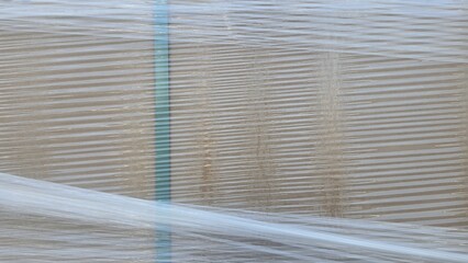 Clear plastic wraps brown cardboard box, close-up texture, parcel box.