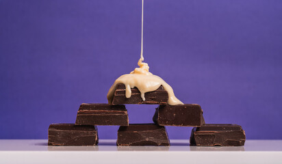 Delicious Chocolate Bars Stacked With Cream Drizzle Against Purple Background