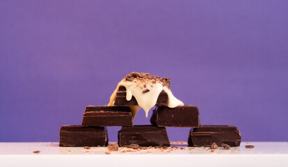 Pile of Chocolate Pieces Topped with Cream Against Purple Background