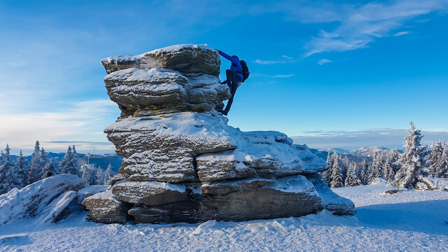 Climber man ascends snow-covered Teufelstein rock formation in Styria, Austria. Serene winter landscapes in remote Fischbach Alps. Unique rocks telling legend about devil. Wilderness in Austrian Alps - Powered by Adobe