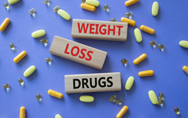 Medicine symbol. Concept words Weight Loss Drugs on wooden blocks. Beautiful purple background with...