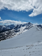 Snowy slopes and peaks in the Polish Tatras, a vibrant winter alpine scene under a blue sky.