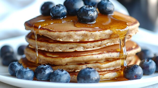 Gluten free homemade almond flour pancakes stacked fresh blueberries and honey drizzle on a white plate