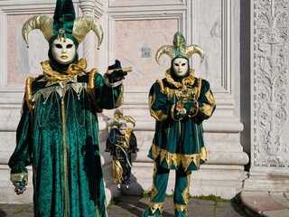 Obraz premium Venice, Italy - People dressed in carnival masks are photographed by tourists in the scenery of the ancient Venetian palaces