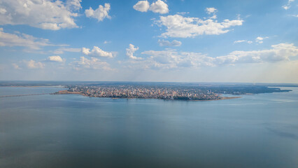 High angle aerial view of a densely populated area of Encarnación city, Paraguay, with the Paraná River and a distant view of Posadas city, Argentina, visible in the background.