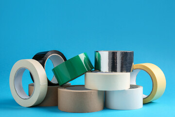 Rolls of different adhesive tapes on light blue background
