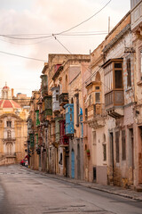 Fototapeta premium The nearly empty St. Margaret Street in Cospicua. Perhaps a reflection of the times. Triq Santa Margerita, Bormla.Cospicua,View at St Paul's Church Cospicua through a street with many colorful bay 