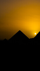 Incredible bright orange sunset on the Giza pyramids in Egypt. Sunset in Cairo. Silhouette of pyramids