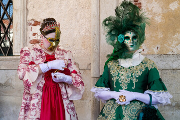 Venice, Italy - People dressed in carnival masks are photographed by tourists in the scenery of the ancient Venetian palaces