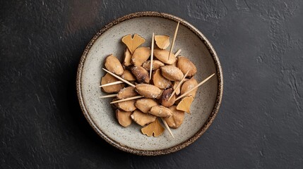 Top down view of Japanese ginkgo nuts roasted salted arranged neatly on a small ceramic plate with toothpicks