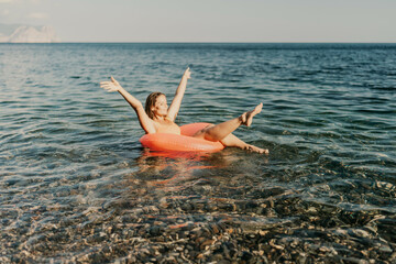 A woman is floating in a red inflatable tube in the ocean