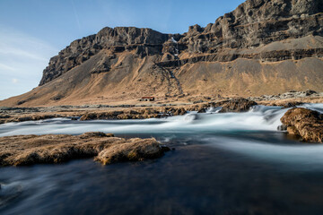 a small river in the south of Iceland with an old barn in the background