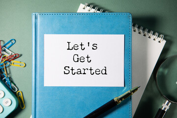 White notebook with the text LET IS GET STARTED on the table